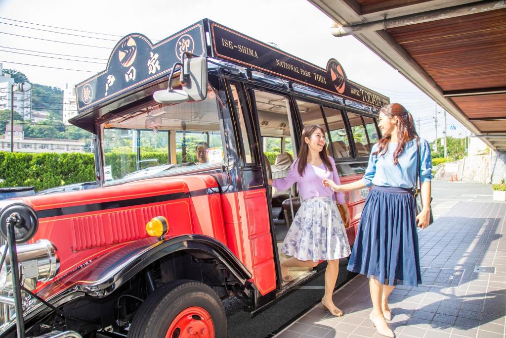 Deux filles se tiennent devant un bus scolaire dans l'établissement Todaya, à Toba