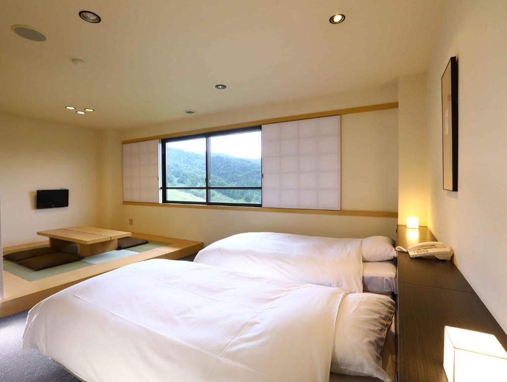 une chambre avec un grand lit blanc et une fenêtre dans l'établissement Manza Onsen Nisshinkan, à Tsumagoi 33 autres photos