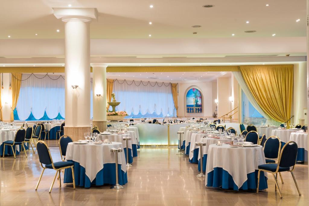 une salle de banquet avec des tables et des chaises blanches dans l'établissement Sant Alphio Garden Hotel & SPA, à Giardini Naxos