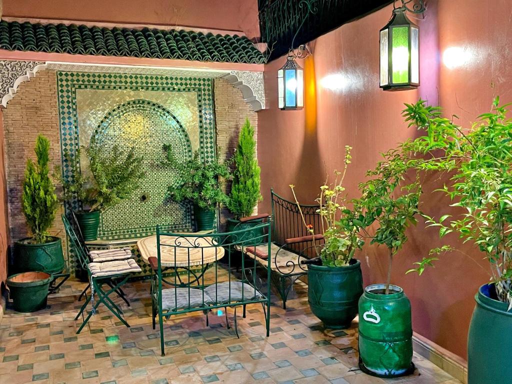 un patio avec une table, des chaises et des plantes en pot dans l'établissement Riad Dar Guennoun, à Fès