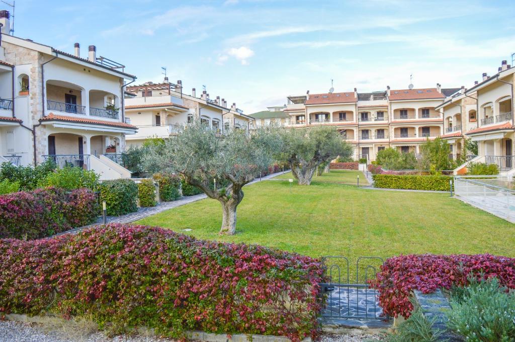 un jardin en face d'un grand bâtiment dans l'établissement Homiday - Residence Micaene, à Pineto