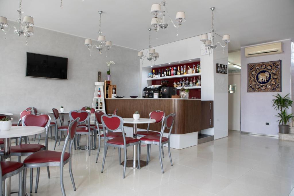 un restaurant avec des chaises et des tables rouges ainsi qu'un bar dans l'établissement Hotel Perla Dello Ionio, à Torre Lapillo