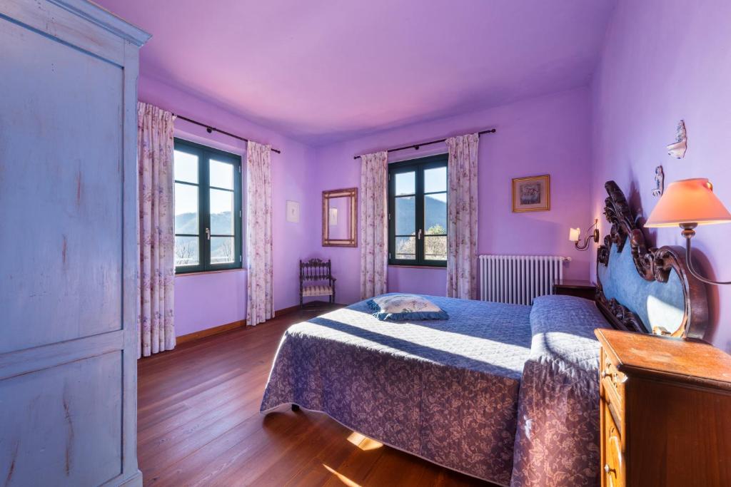 - une chambre avec des murs violets, un lit et des fenêtres dans l'établissement Villa Popiglio by Mmega, à San Marcello Pistoiese