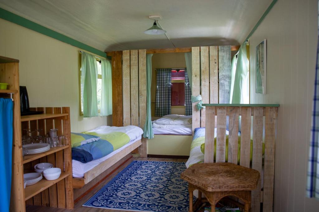 - une chambre avec 2 lits et une chaise dans l'établissement le bon chemin roulotte, à Fage