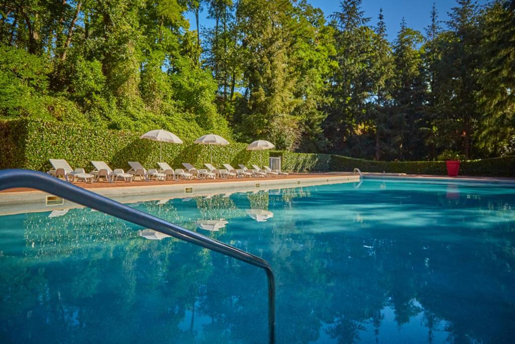 une piscine avec chaises longues et parasols dans l'établissement Tiki House M-Home-Climatisé - Belle parcelle !, à Saint-Chéron