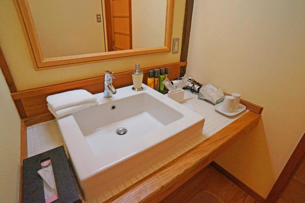 une salle de bain avec un lavabo blanc et un miroir dans l'établissement Mujinzo, à Yufu