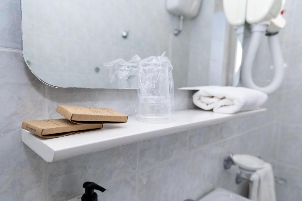 une salle de bain avec une étagère avec des serviettes et un miroir dans l'établissement Hotel Royal, à Giulianova