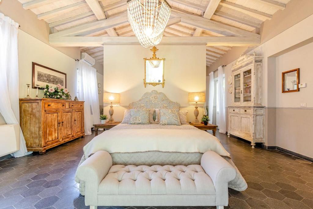 - une grande chambre avec un lit blanc et un lustre dans l'établissement Cottage Nanni, Romantic and Luxury with Pool, à Pescia