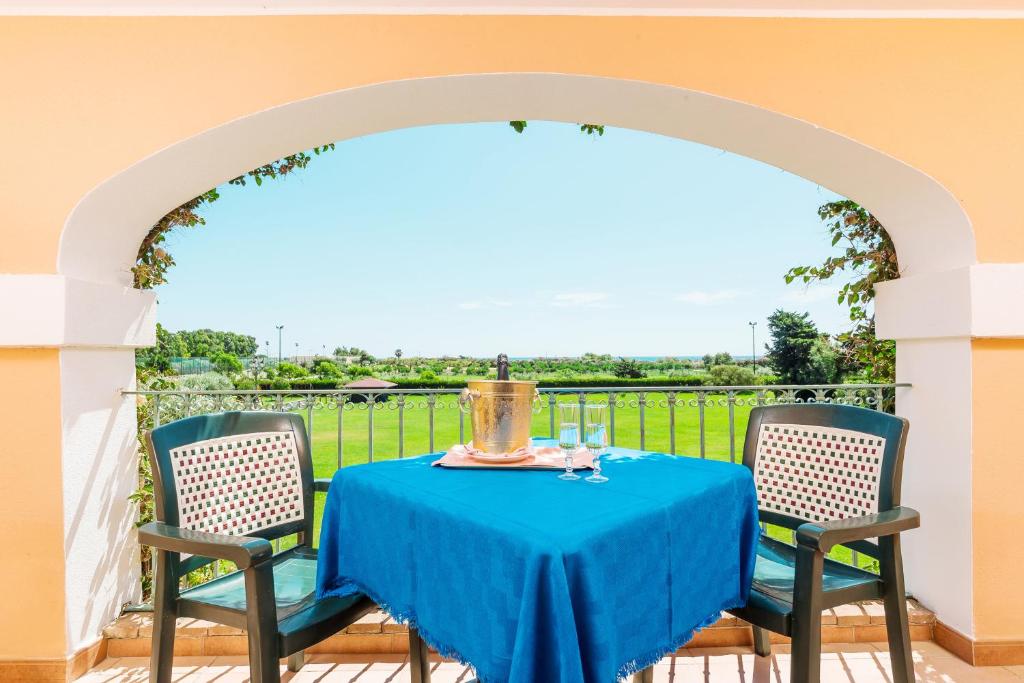 une table avec un chiffon bleu et deux chaises dans l'établissement Sentido Orosei Beach, à Orosei