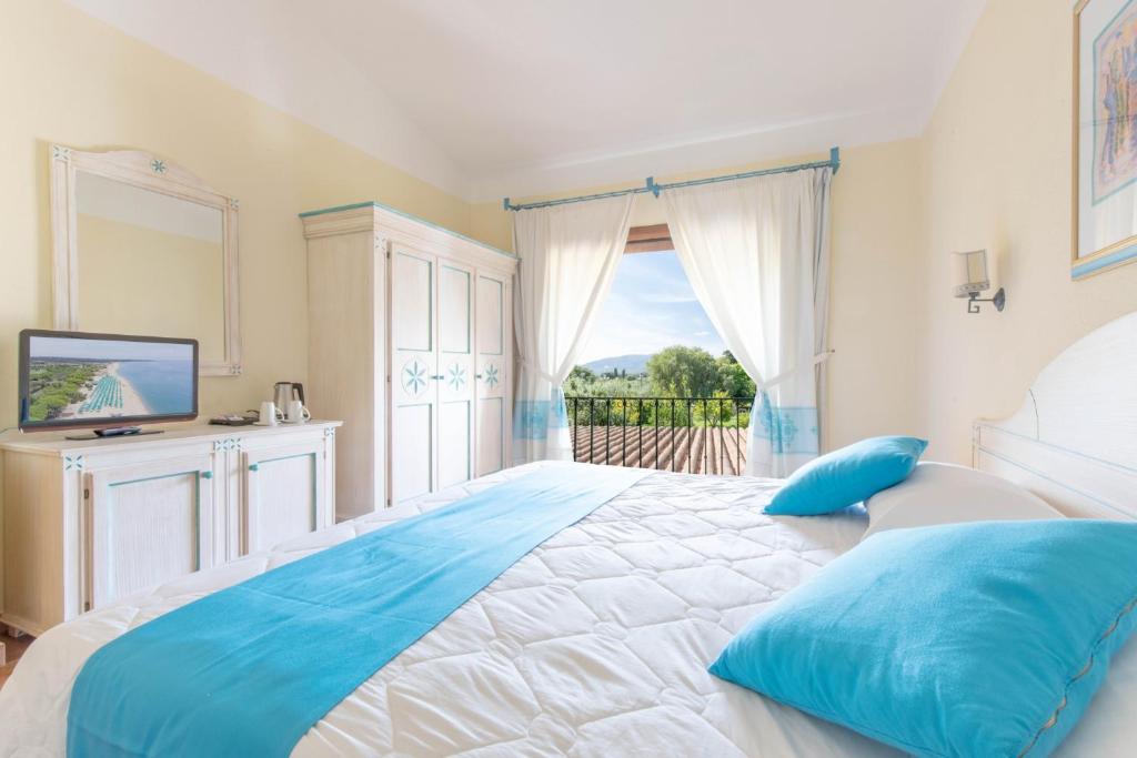 - une grande chambre avec un grand lit et des oreillers bleus dans l'établissement Sentido Orosei Beach, à Orosei