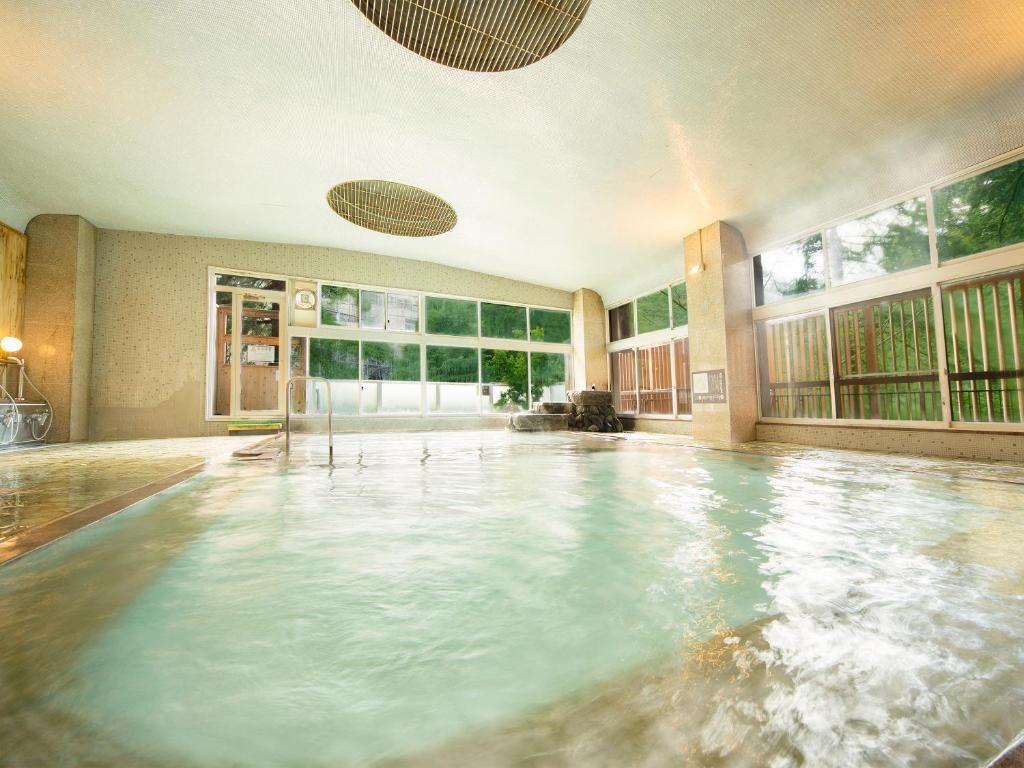 une piscine intérieure avec une grande pièce dotée de fenêtres dans l'établissement Ooedo Onsen Monogatari Unazuki Grand Hotel, à Kurobe
