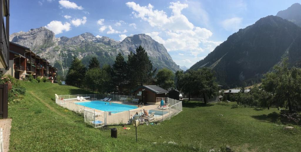 une piscine dans un champ avec des montagnes en arrière-plan dans l'établissement Le Bouquetin 73 Appartement cosy type chalet avec piscine au pied des pistes et superbe vue panoramique, à Pralognan-la-Vanoise