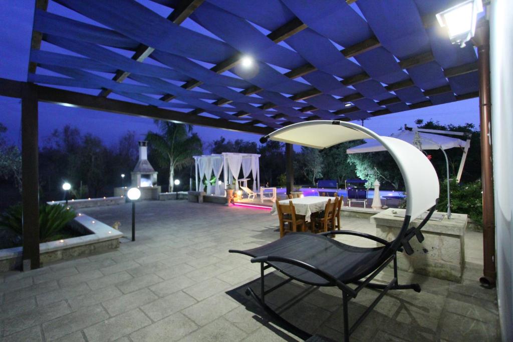 une terrasse avec une chaise sous une pergola la nuit dans l'établissement Villa Luisa villa con piscina e Vasca Idromassaggio vicino Otranto, à Carpignano Salentino