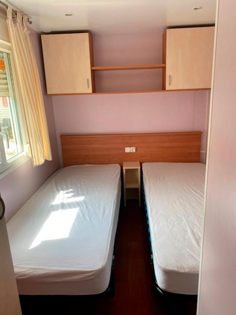 une petite chambre avec deux lits et une fenêtre dans l'établissement Agréable mobile-home sans vis-à-vis, 3 chambres, à Argelès-sur-Mer