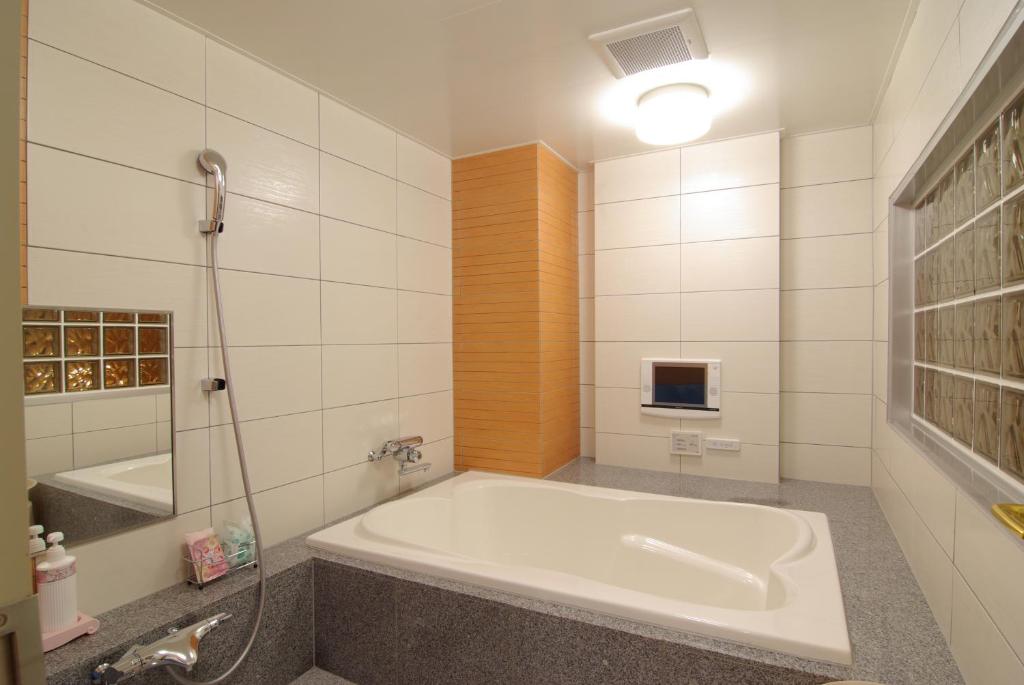 une salle de bain blanche avec une baignoire et une douche dans l'établissement Shonan Sirene (Adult Only), à Hiratsuka