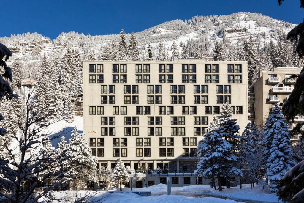 un grand bâtiment dans la neige avec une montagne dans l'établissement RockyPop Flaine Appartements & Spa, à Flaine