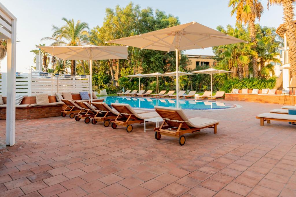 un groupe de chaises et de parasols à côté d'une piscine dans l'établissement Le Dune Sicily Hotel, à Catane