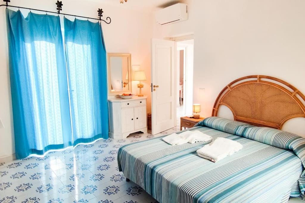 une chambre avec un grand lit avec des rideaux bleus dans l'établissement Villa Conchiglia blu con piscina, à Ischia 143 autres photos