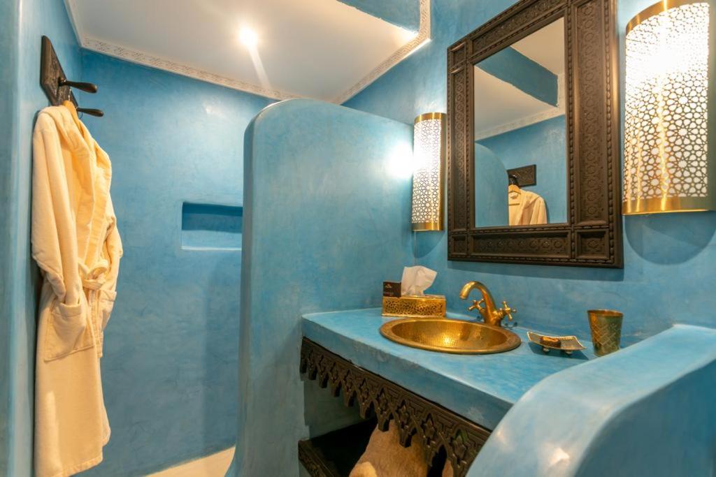une salle de bain bleue avec un lavabo et un miroir dans l'établissement Riad Hart Essoura, à Marrakech 37 autres photos