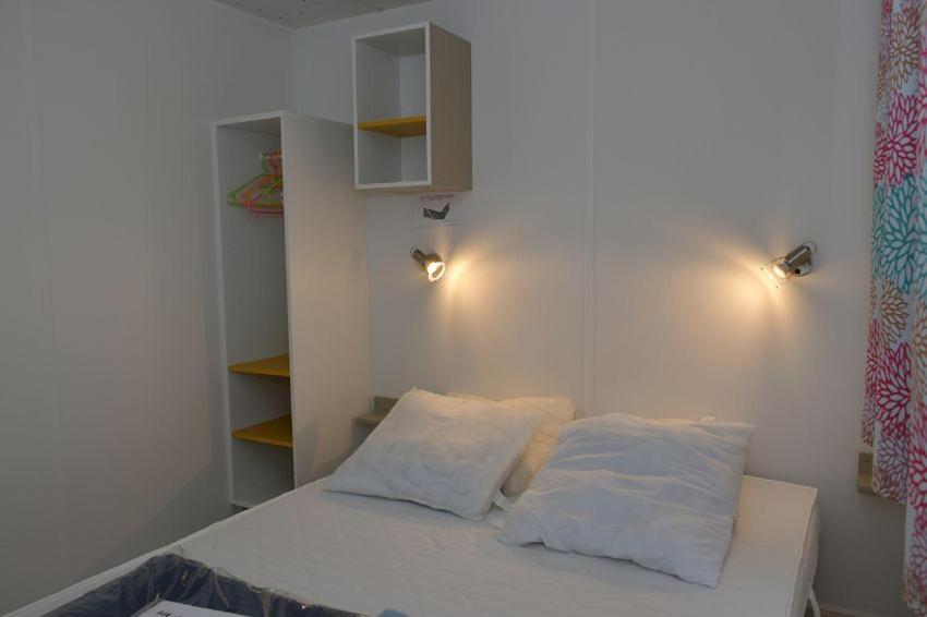 une chambre avec un lit avec deux oreillers dessus dans l'établissement Camping Le Puits Rochais, à Les Sables-dʼOlonne