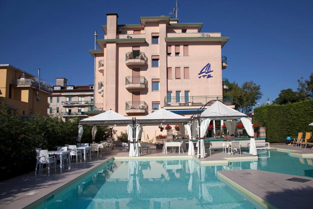 un hôtel avec une piscine devant un bâtiment dans l'établissement Ute Hotel, à Lido di Jesolo