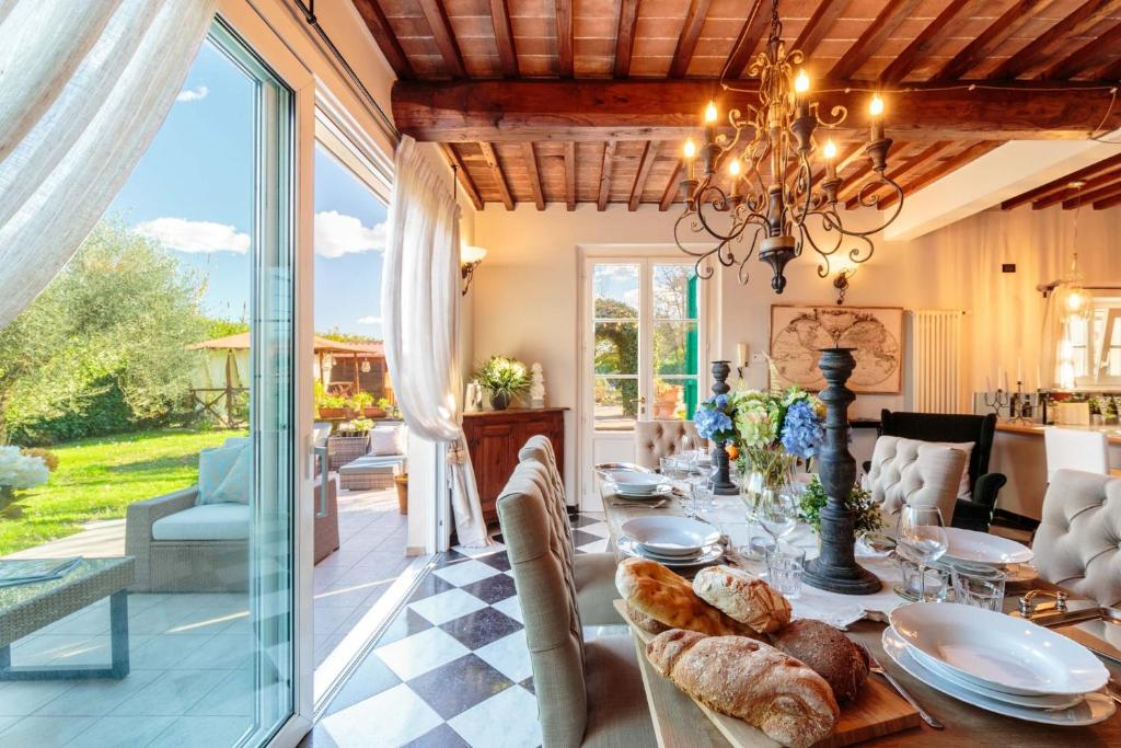 une salle à manger avec une table et un lustre dans l'établissement Villa Catia Farmhouse, Three Luxury Bedrooms, a Jacuzzi Pool and a Dream-Like Getaway Experience, à Capannori
