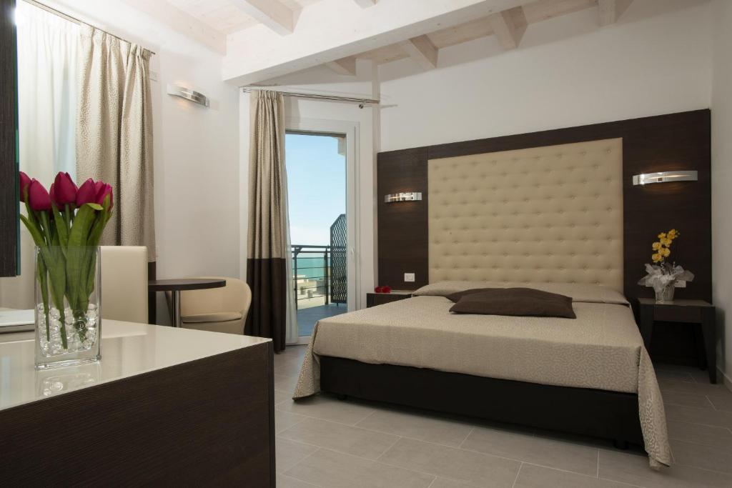 - une chambre avec un lit et un vase de fleurs dans l'établissement Hotel Sheila, à Lido di Jesolo