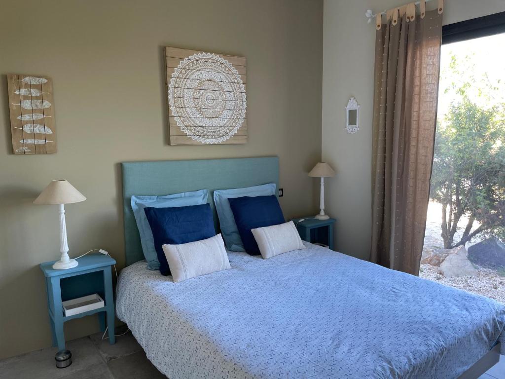 une chambre avec un lit bleu avec deux tables et une fenêtre dans l'établissement Le Domaine du Cade - Gîtes d'exception 4 étoiles "Le Lodge du Cade ", à Cazevieille 37 autres photos