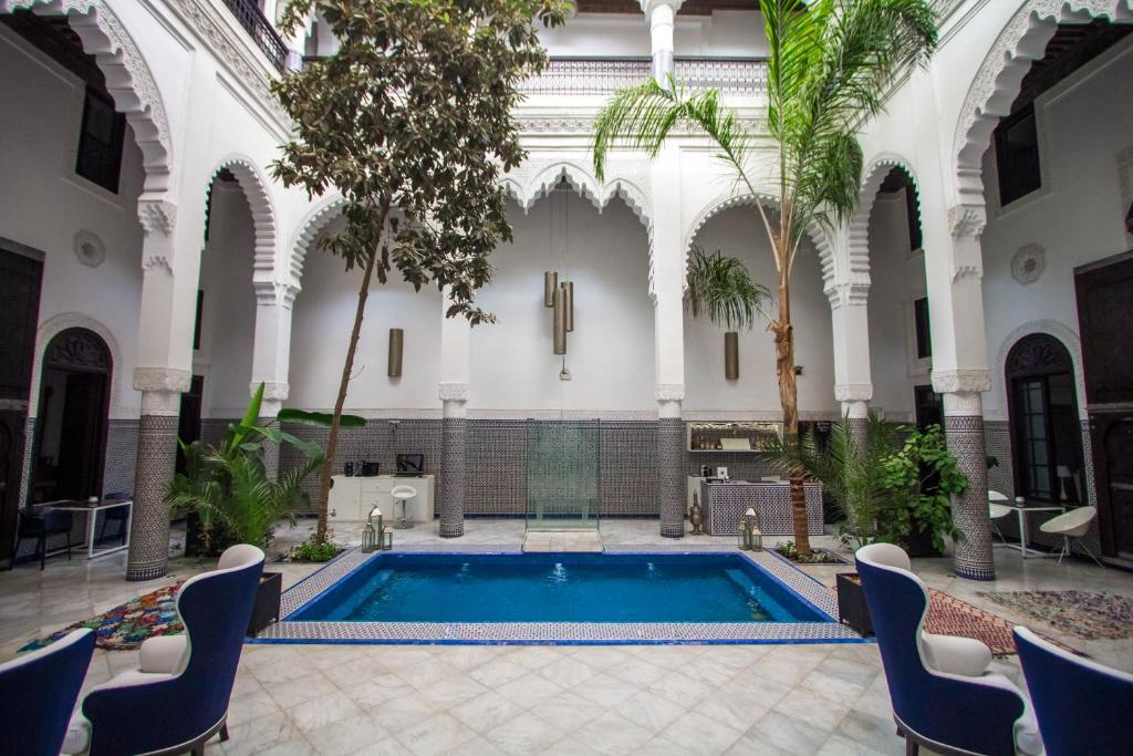 - une piscine dans un bâtiment avec des chaises et des arbres dans l'établissement Riad Braya, à Fès