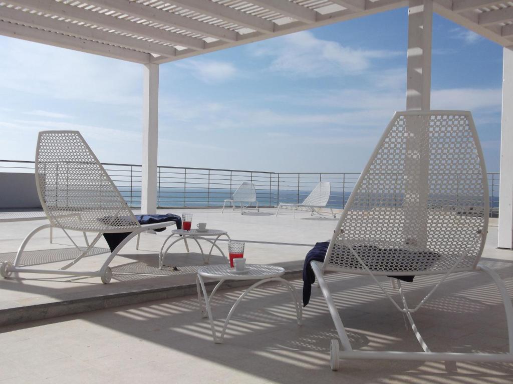deux chaises et une table sur une terrasse avec l'océan dans l'établissement Brezza Di Grecale, à Trapani