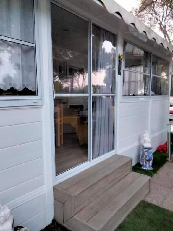 - une porte d'entrée d'une maison avec une terrasse couverte en bois dans l'établissement Camping L'Oasis 5 étoiles à Puget-sur-Argens, à Puget-sur Argens