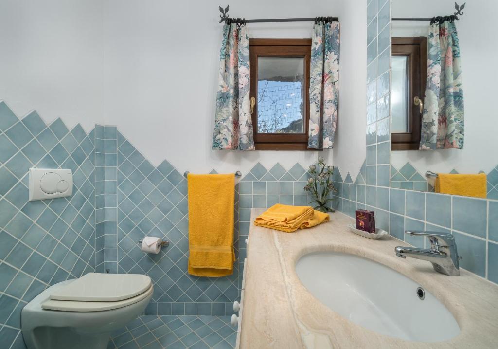 une salle de bain bleue avec un lavabo et des toilettes dans l'établissement Sardinia Family Villas - Villa Gaia with private pool in the countryside, à Sant Antonio Di Gallura 23 autres photos