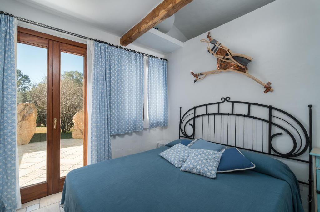 - une chambre avec un lit bleu et une porte coulissante en verre dans l'établissement Sardinia Family Villas - Villa Eloisa with private pool, à San Pantaleo