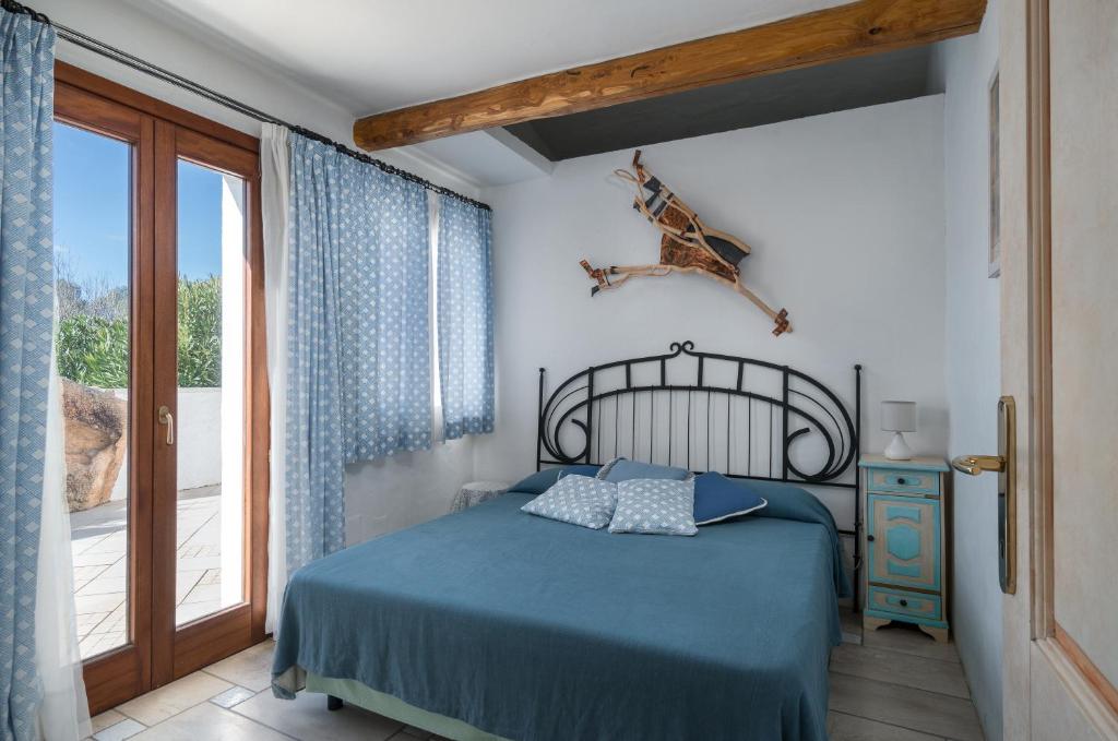 une chambre avec un lit bleu et une fenêtre dans l'établissement Sardinia Family Villas - Villa Eloisa with private pool, à San Pantaleo
