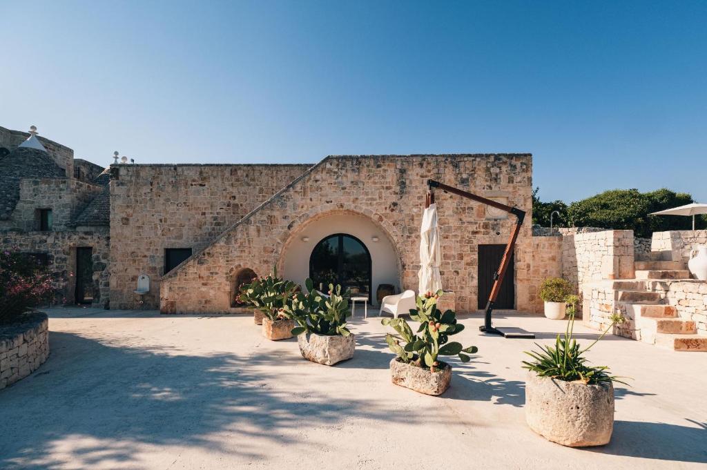 un bâtiment en briques avec des plantes en pot dans une cour dans l'établissement HelloAPULIA - Masseria Minetta, Scenic Villa Escape - Pet friendly, à Cisternino