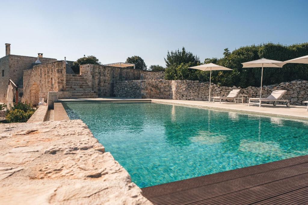 - une piscine avec 2 chaises longues et des parasols dans l'établissement HelloAPULIA - Masseria Minetta, Scenic Villa Escape - Pet friendly, à Cisternino