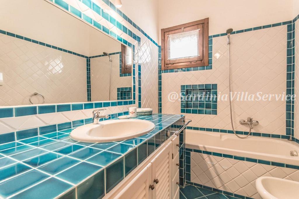 une salle de bain carrelée bleue avec un lavabo et une baignoire dans l'établissement Villa Cala Granu - Porto Cervo, à Porto Cervo