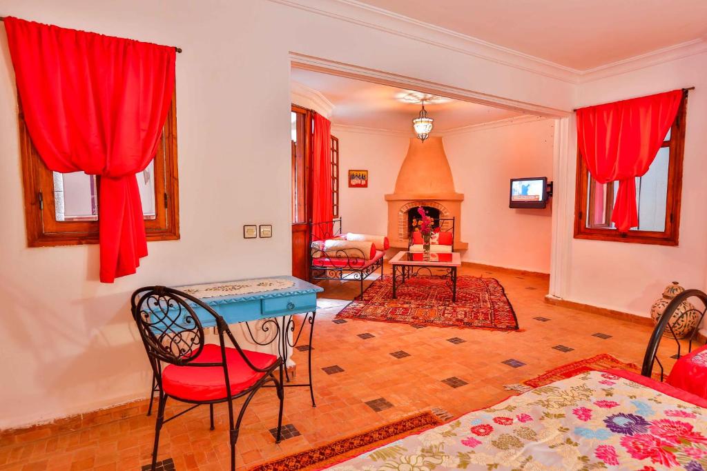 - un salon avec des rideaux rouges, une table et des chaises dans l'établissement Riad Al khansaa, à Essaouira