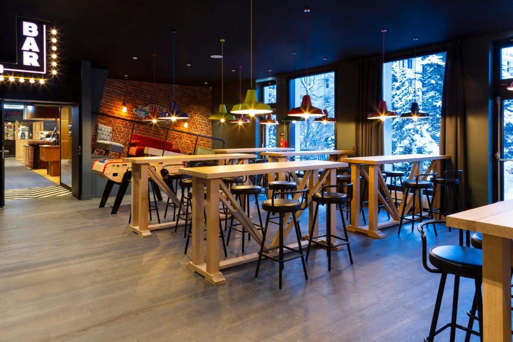 un bar avec des tables et des chaises en bois dans un restaurant dans l'établissement RockyPop Flaine Hotel & Spa, à Flaine