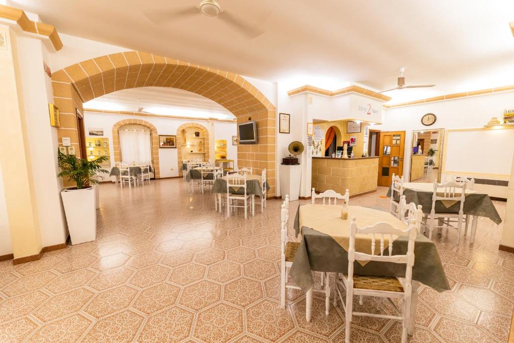 une grande pièce avec tables et chaises et une cuisine dans l'établissement Albergo 2 Mari, à Leuca