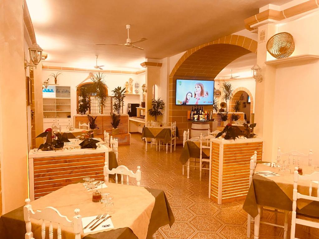 un restaurant avec des tables, des chaises et une télévision dans l'établissement Albergo 2 Mari, à Leuca