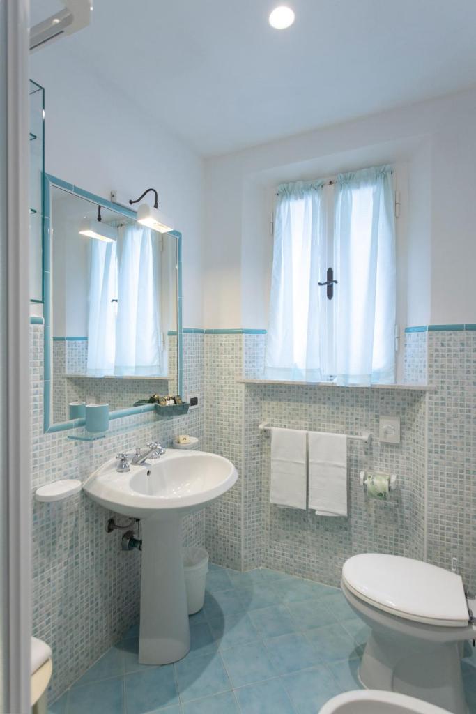 une salle de bain avec un lavabo, des toilettes et un miroir dans l'établissement Hotel Valle Verde, à Procchio