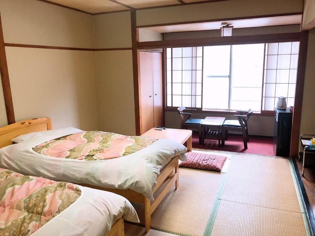 une chambre avec deux lits et une salle à manger avec une table dans l'établissement Shiobara Onsen Hotel Ohruri, à Nasushiobara