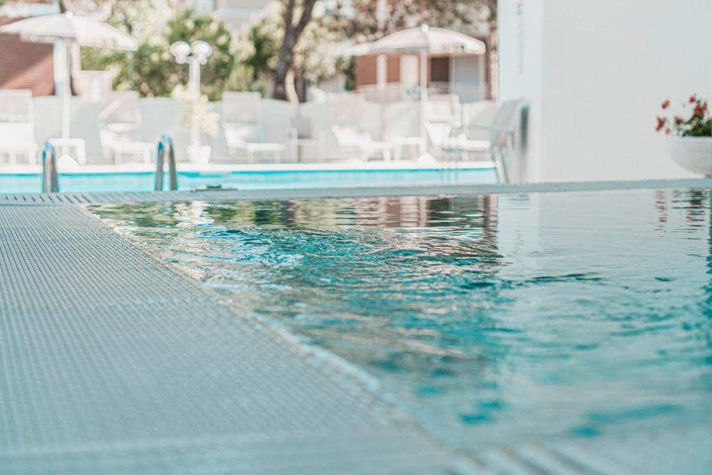 - une piscine avec des chaises blanches et un peu d'eau dans l'établissement Hotel San Giorgio, à Milano Marittima 76 autres photos