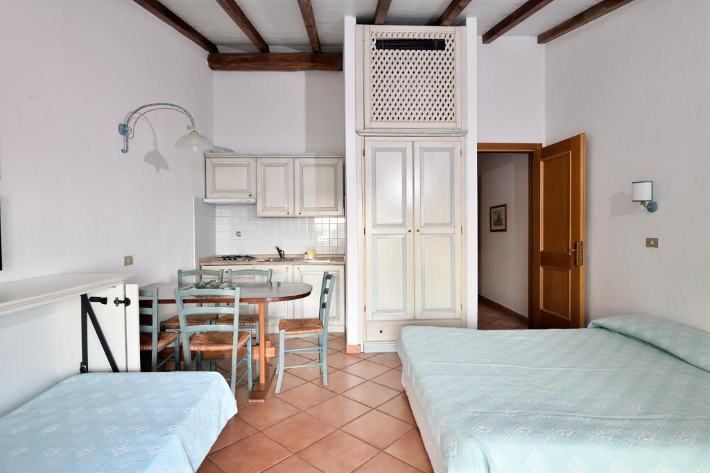 Cette chambre comprend une cuisine et une table avec des chaises. dans l'établissement Baia Caddinas Clubresidence, à Golfo Aranci 43 autres photos