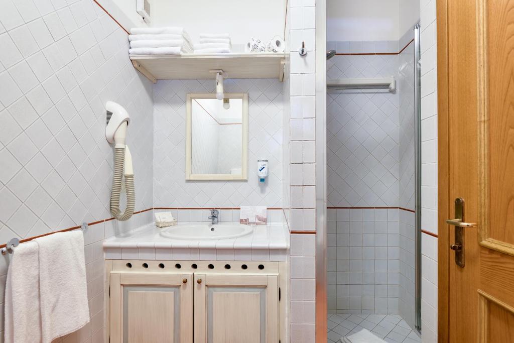 une salle de bain blanche avec lavabo et douche dans l'établissement Baia Caddinas Clubresidence, à Golfo Aranci