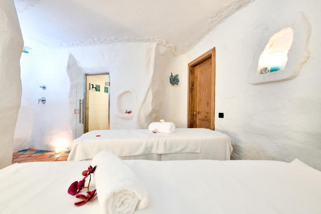 deux lits dans une chambre aux murs blancs dans l'établissement Baia Caddinas Clubresidence, à Golfo Aranci