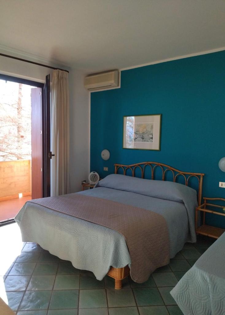 une chambre avec un grand lit avec un mur bleu dans l'établissement Albergo Il Biancospino, à Sirmione