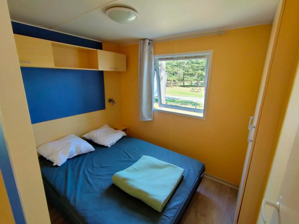 - une petite chambre avec un lit bleu et une fenêtre dans l'établissement Mobil-home 6 pers Coeur de Vendée, à Le Pont Legé