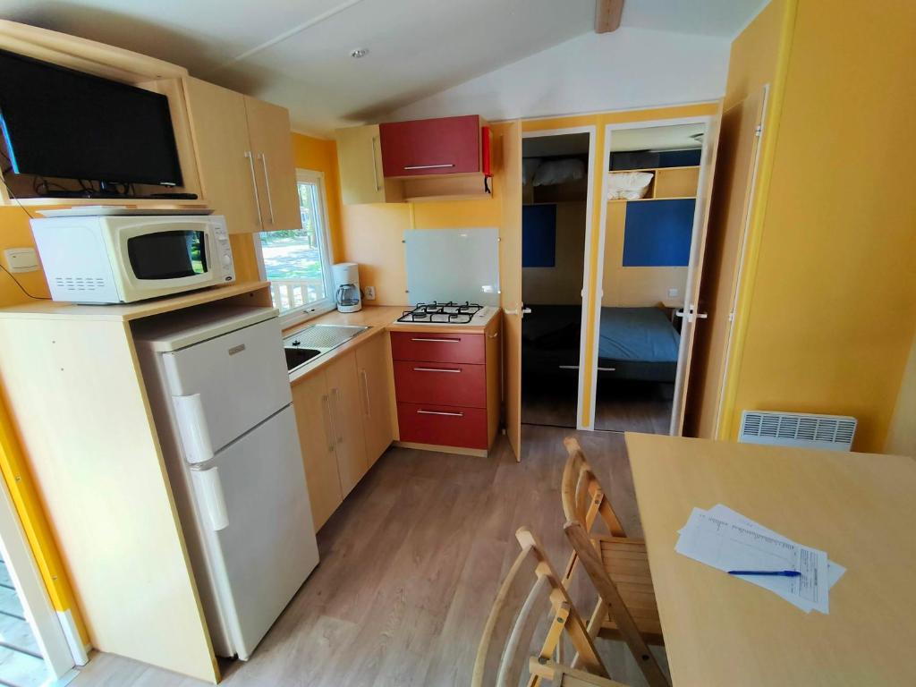 La cuisine est équipée d'un réfrigérateur, d'un four micro-ondes et d'une table. dans l'établissement Mobil-home 6 pers Coeur de Vendée, à Le Pont Legé